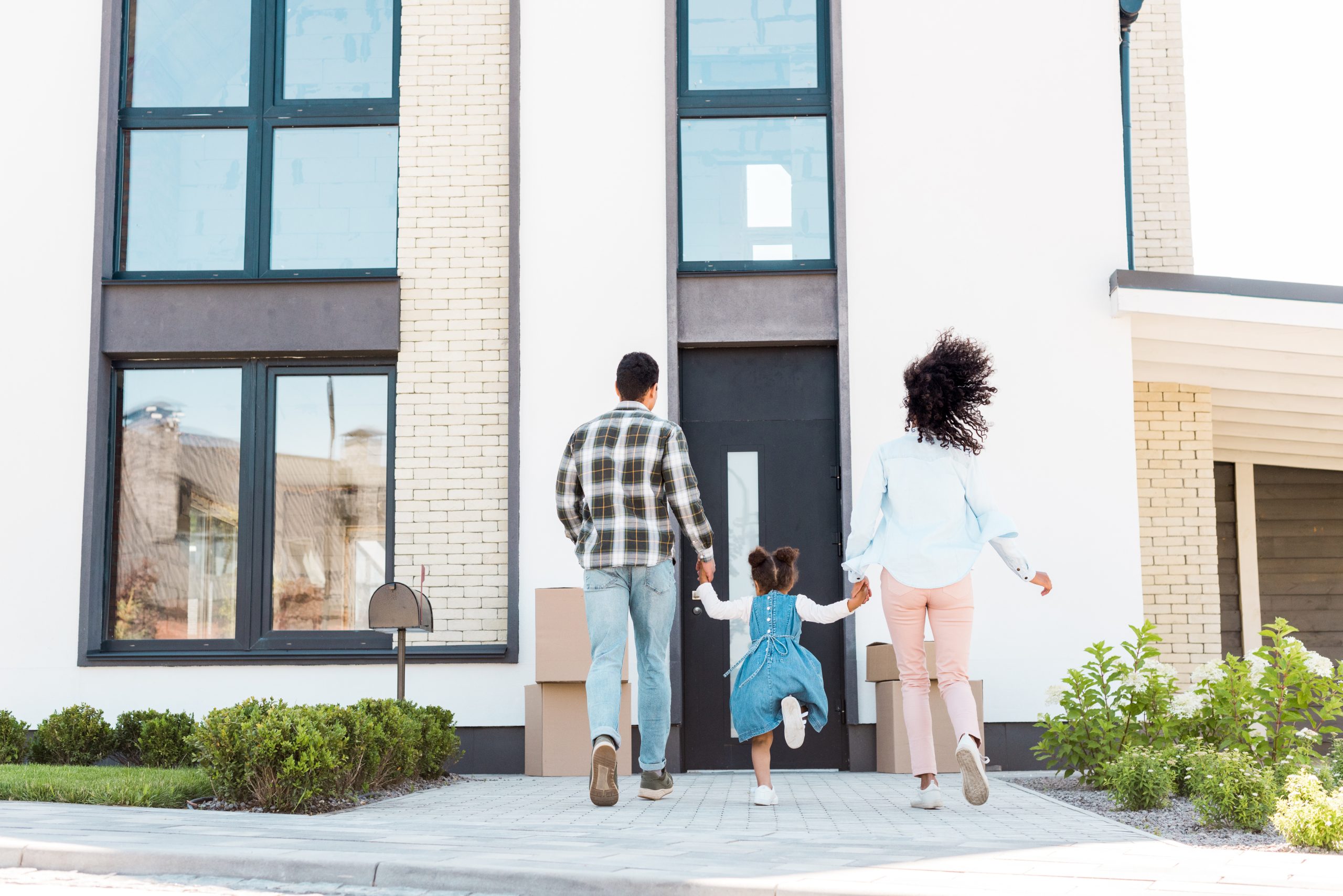 back view of african american couple with child running to new house