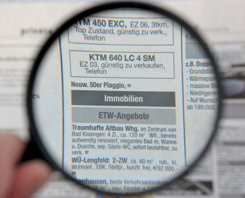 Lupe, die eine Immobilienanzeige vergrößert