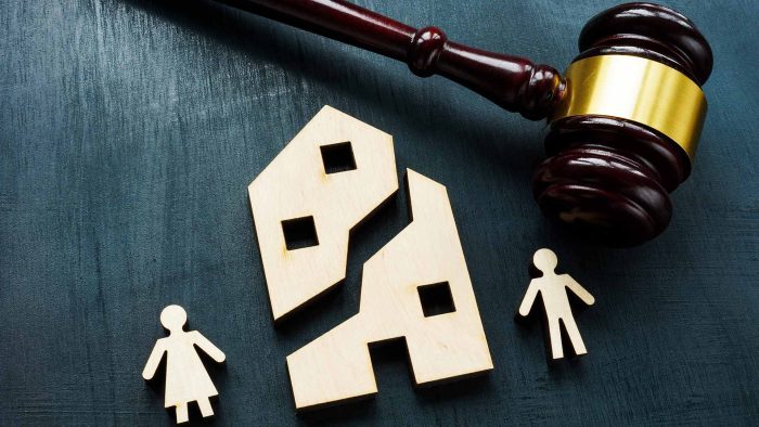 Zerbrochenes Modellhaus mit Richterhammer als Symbol für Scheidungsimmobilien