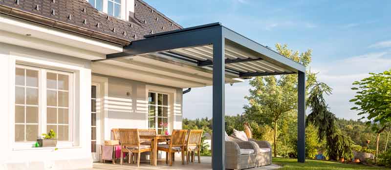 Überdachte Terrasse eines Einfamilienhauses mit Sitzgruppe aus hellem Holz