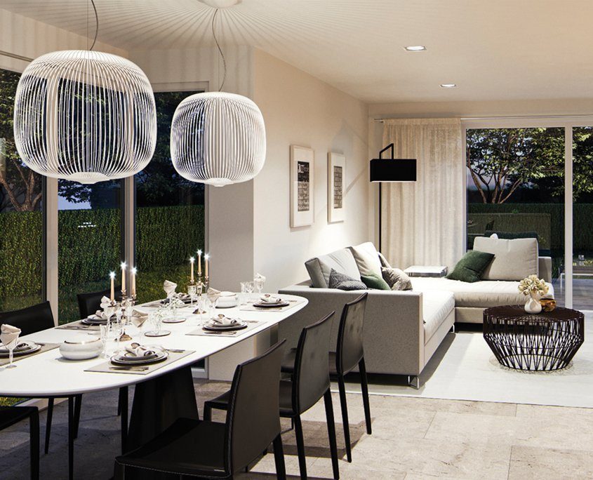 Moderner offener Wohn- und Essbereich mit elegantem Interieur; großer weißer Esstisch mit schwarzer Bestuhlung und stilvollen Hängelampen, gemütliches graues Ecksofa mit Couchtisch im Wohnzimmerbereich, helle Fliesenböden und große Fensterfronten, die den Raum mit natürlichem Licht durchfluten.