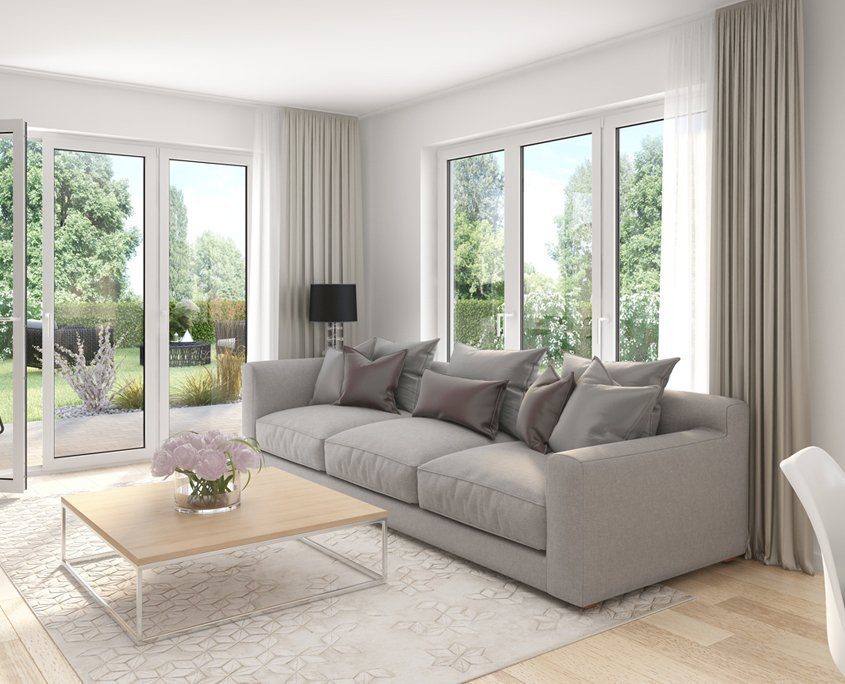 Helles Wohnzimmer mit großen, bodentiefen Fenster Elementen. Ein graues Sofa mit einem minimalistischen, hellen Holztisch davor