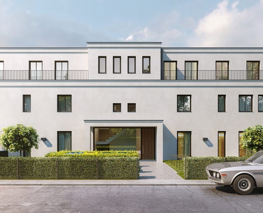 Frontansicht eines hellen Mehrfamilienhausen mit dunkeln Fenster Elementen und einer grünen Hecke davor.