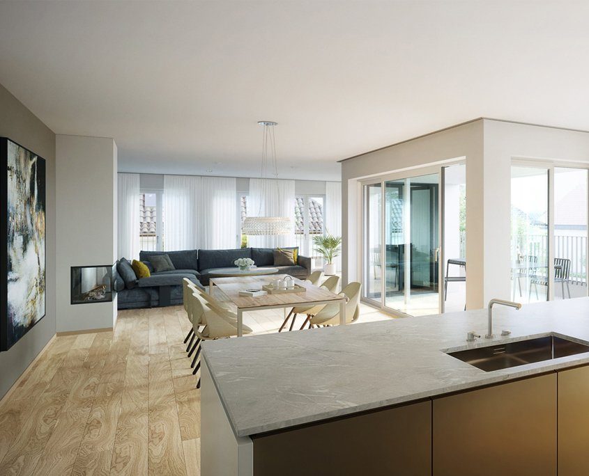 Offener Wohn- und Essbereich mit modernem Design. Im Vordergrund eine Kücheninsel mit grauer Steinoberfläche und eingelassenem Spülbecken. Der Essbereich mit einem großen Holztisch und mehreren hellen Stühlen liegt zwischen der Küche und einer großen Fensterfront, die zu einem Balkon führt. Im Hintergrund ein gemütliches Wohnzimmer mit Ecksofa in Grau, dekoriert mit Kissen. An der Wand hängt ein großes, abstraktes Kunstwerk, und ein moderner Kamin ist eingebaut.