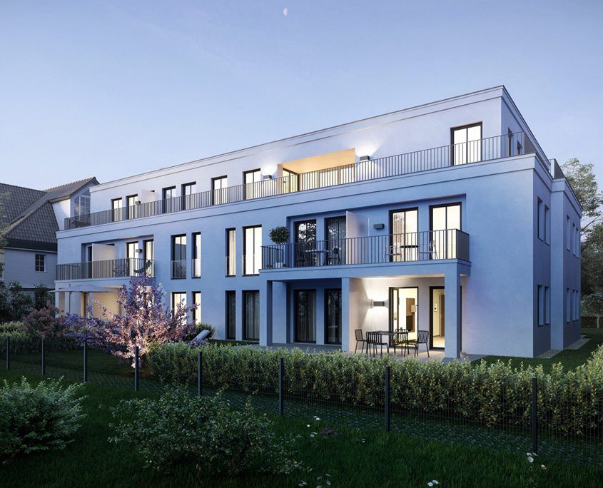 Gartenansicht eines hellen Mehrfamilienhauses in der Abenddämmerung. Fensterrahmen und Balkon sind dunkelgrau.