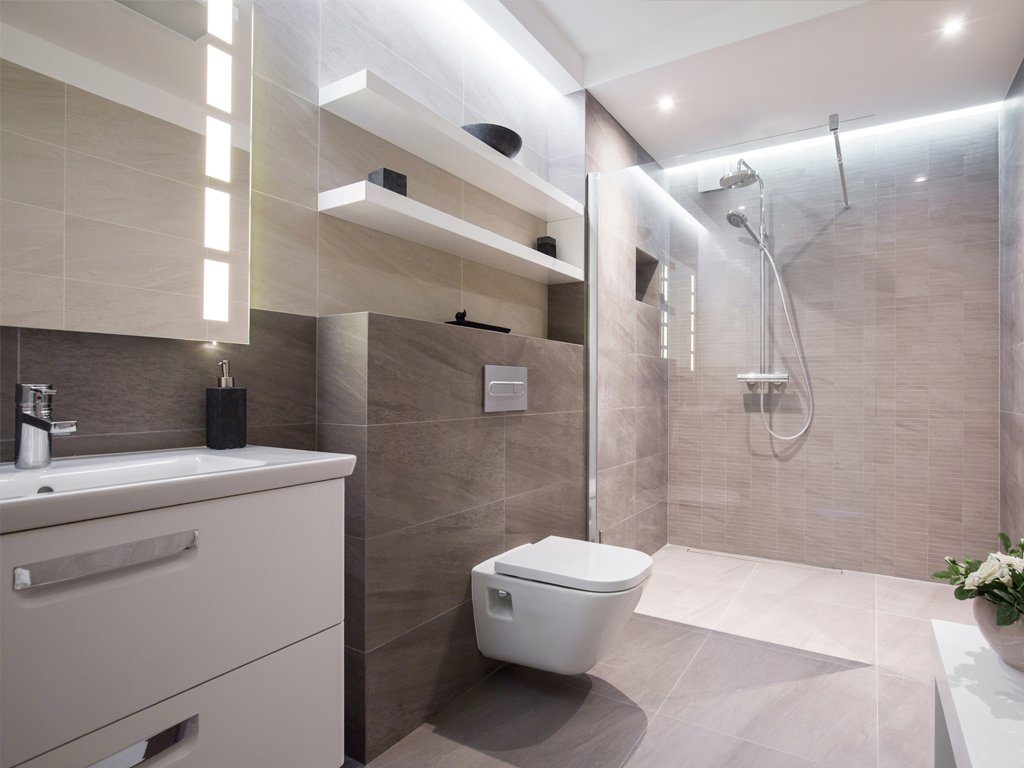Modernes, grau gefliestes Badezimmer mit weißem Waschbecken und weißer WC Garnitur, sowie einer ebenerdigen Dusche