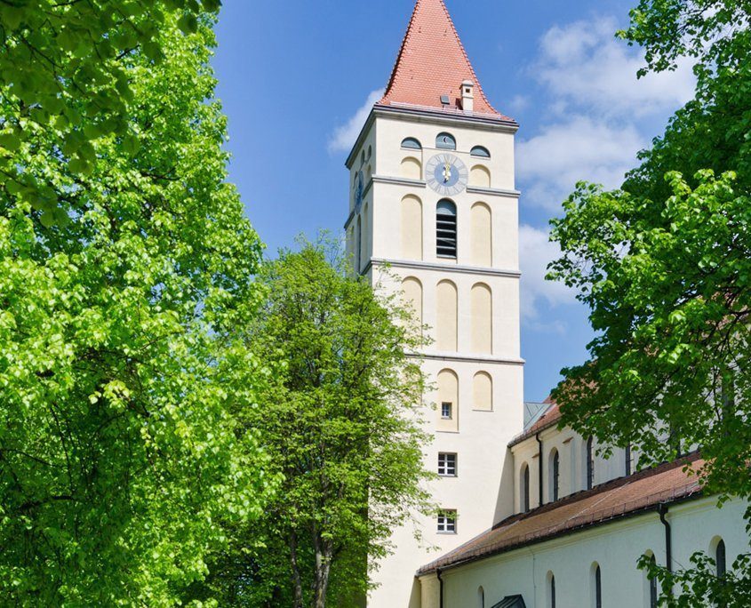 Hell verputzter Kirchturm mit rotem Ziegeldach