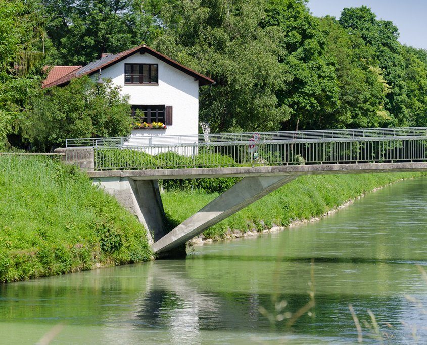 Kleines, weißes Häuschen an einer Brücke im Grünen