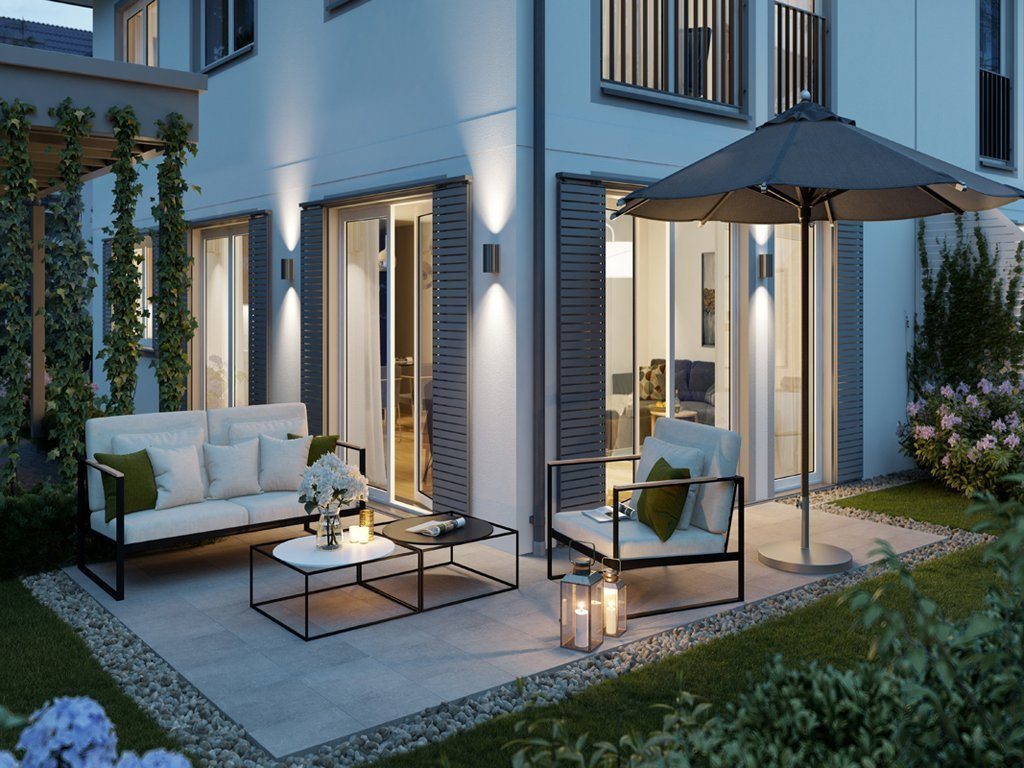 Blick auf eine erleuchtete Neubau-Terrasse am Abend mit grauem Schirm und eleganten weißen Möbeln