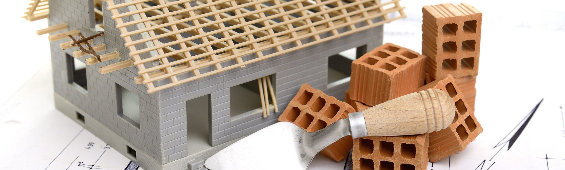 Miniaturhaus mit Plan und Ziegelsteinen