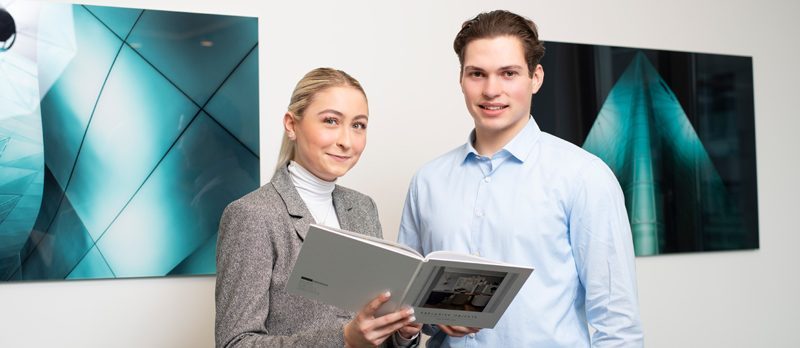 Auszubildende bei Aigner Immobilien Auszubildende bei Aigner Immobilien halten ein exklusives Exposé in den Händen