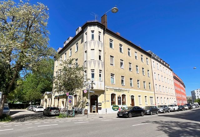 Ansicht eines Eck-Mehrfamilienhauses in München unter blauem Himmel