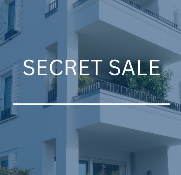 Modernes weißes Wohngebäude mit "Secret Sale" Aufschrift