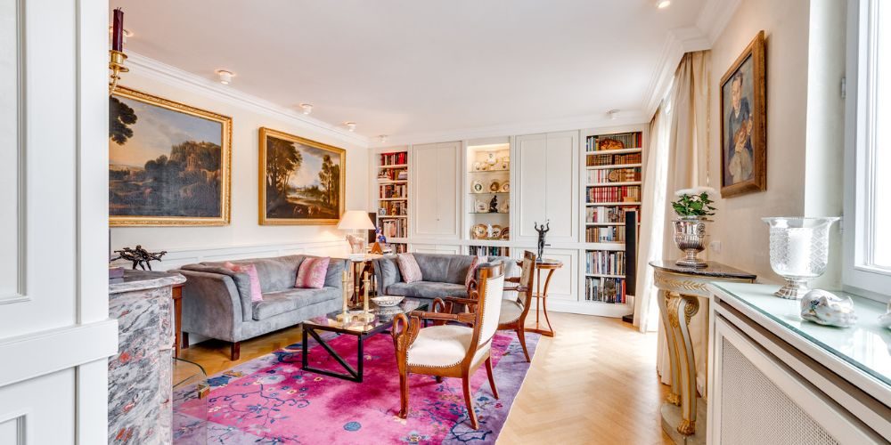 Blick in ein Wohnzimmer einer exklusiven Immobilie mit barocker Einrichtung und Gemälden in goldenen, historischen Rahmen