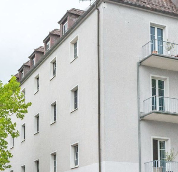 Mehrfamilienhaus in München mit grünen Laubbäumen davor