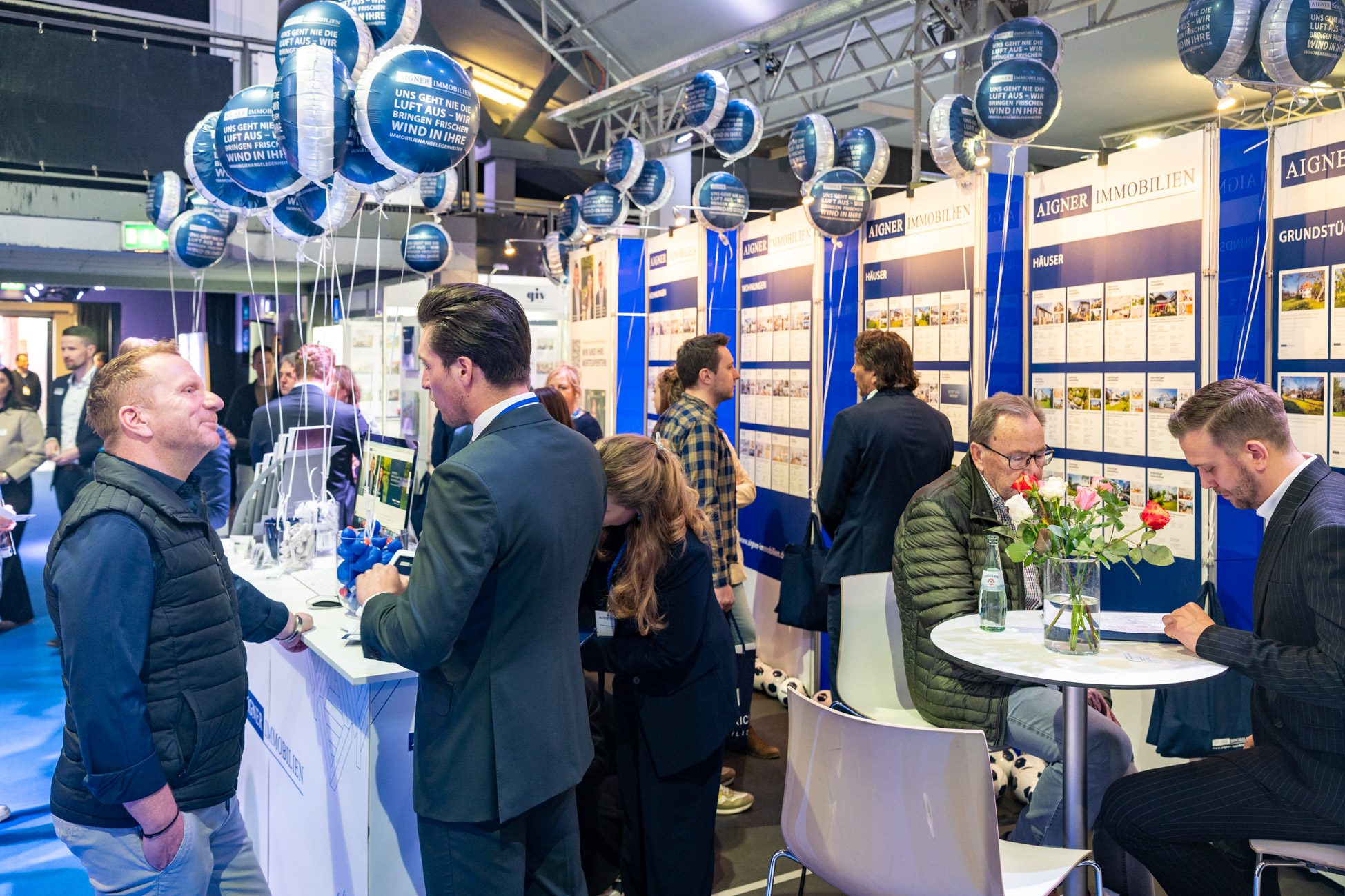 Menschen auf der Münchner Immobilienmesse am Stand von Aigner Immobilien