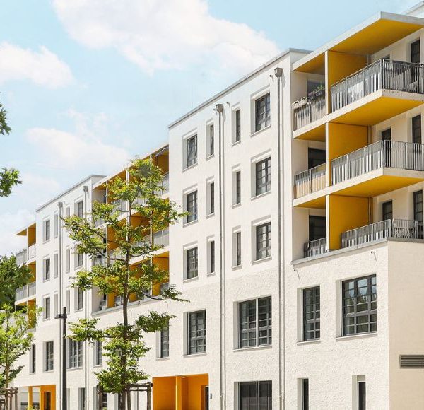 Neubau-Wohnanlage mit Balkonen und Bäumen entlang einer ruhigen Wohnstraße