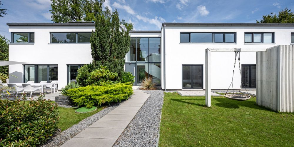 Zweigeschossiges Architektenhaus mit großer Fensterfront, gepflegtem Garten und Schaukel