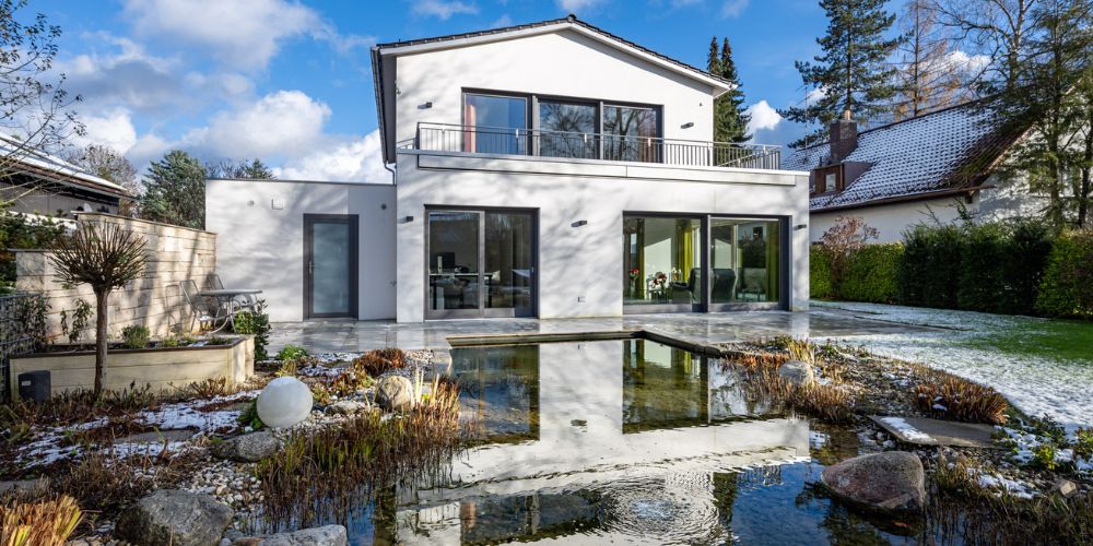 Stilvolle, moderne Villa mit großflächigen Fensterfronten und einem idyllischen Naturteich im gepflegten Garten