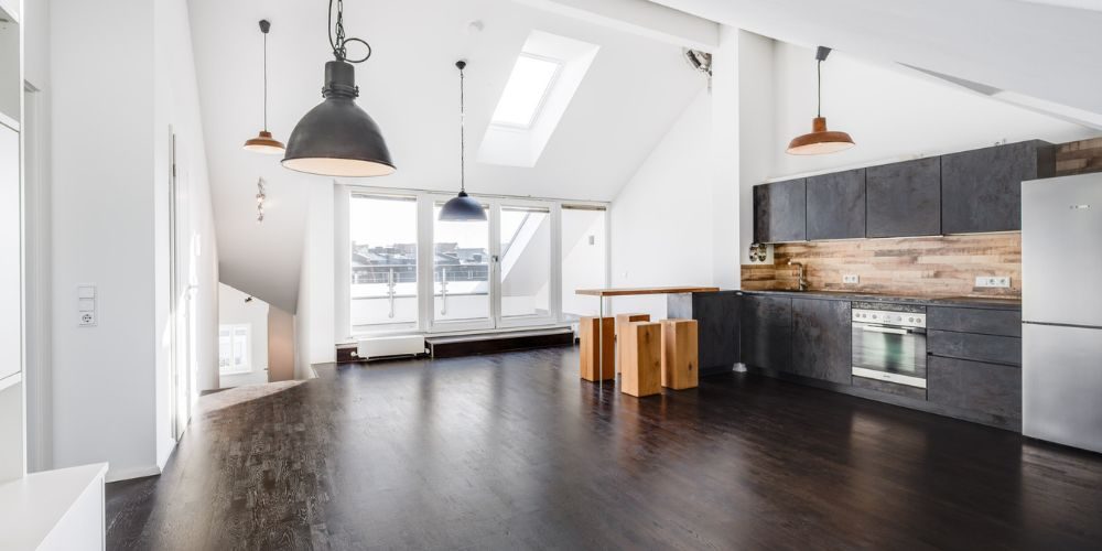 Offener Wohnbereich mit dunklem Parkett, moderner Einbauküche und Zugang zur Dachterrasse – stilvolle Dachgeschosswohnung