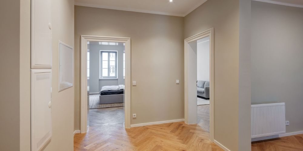 Geräumiger Eingangsbereich mit Parkett im Fischgrätmuster, Blick in Schlafzimmer und Wohnzimmer einer stilvollen Münchner Altbauwohnung