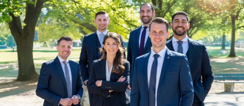 Team Investment der Aigner Immobilien GmbH im Hintergrund grüne Bäume