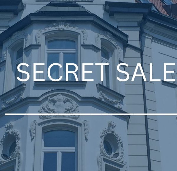 Detailreiche Fassade eines prachtvollen Jugendstil-Altbaugebäudes mit Dachgauben in München, eingefasst von grünen Bäumen, mit dem Schriftzug „Secret Sale“.