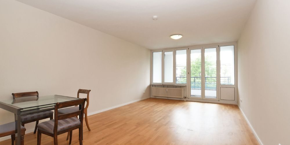 Wohnzimmer mit Parkettboden, Essbereich und großen Fensterfronten mit Zugang zum Balkon