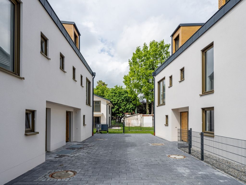 Ruhiger Innenhof mit moderner Pflasterung und Zugang zu mehreren Wohneinheiten in einer Neubauwohnanlage in München-Aubing