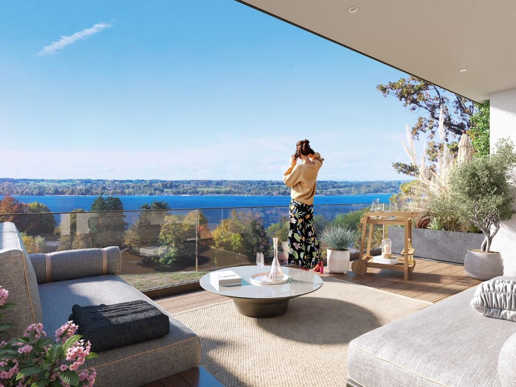 rau genießt den Panoramablick von einer modernen Penthouse-Terrasse auf einen See nahe München, mit stilvoller Outdoor-Lounge und Glasbrüstung
