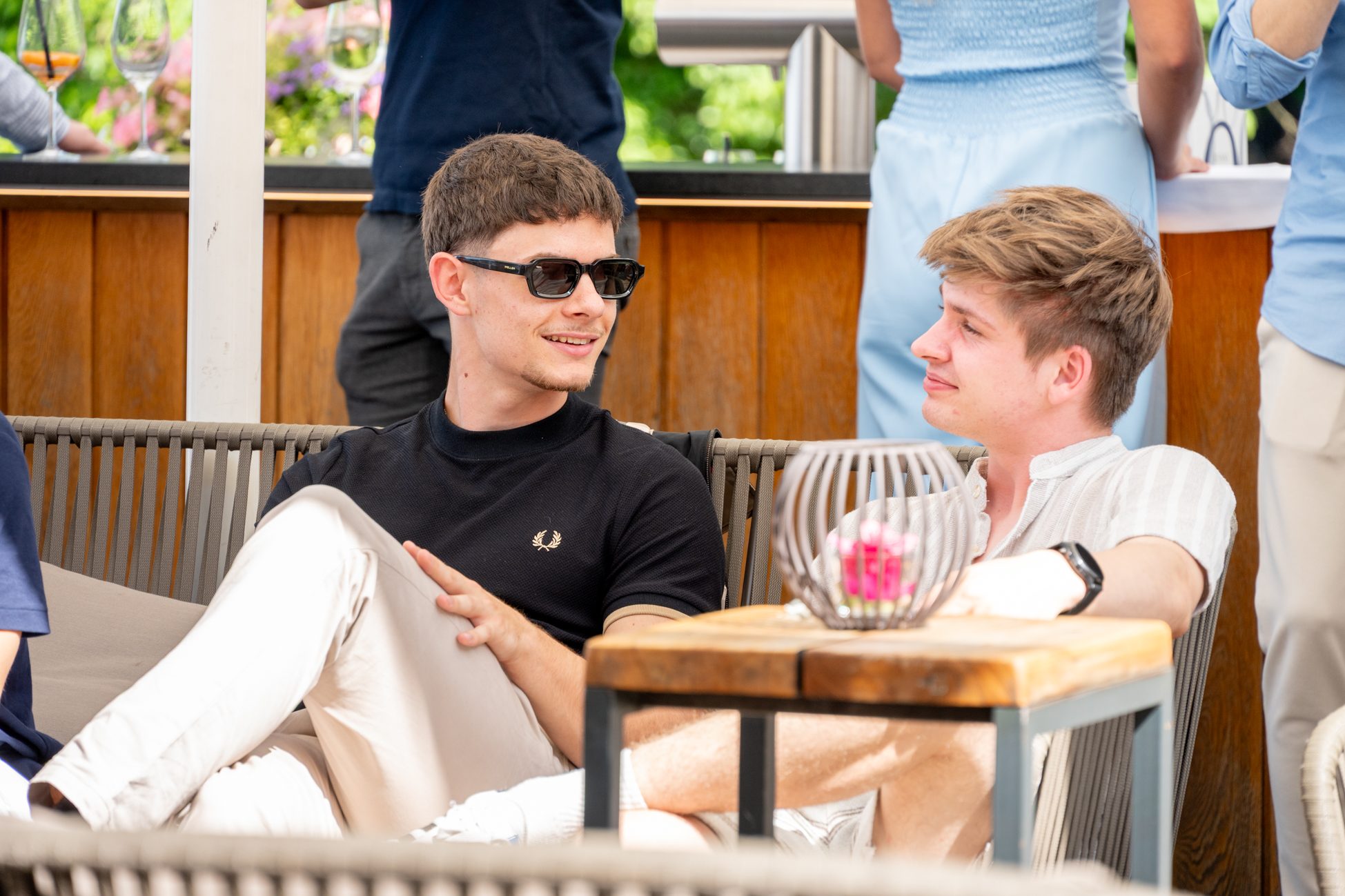 Zwei junge Männer im Gespräch auf einer sonnigen Event-Terrasse