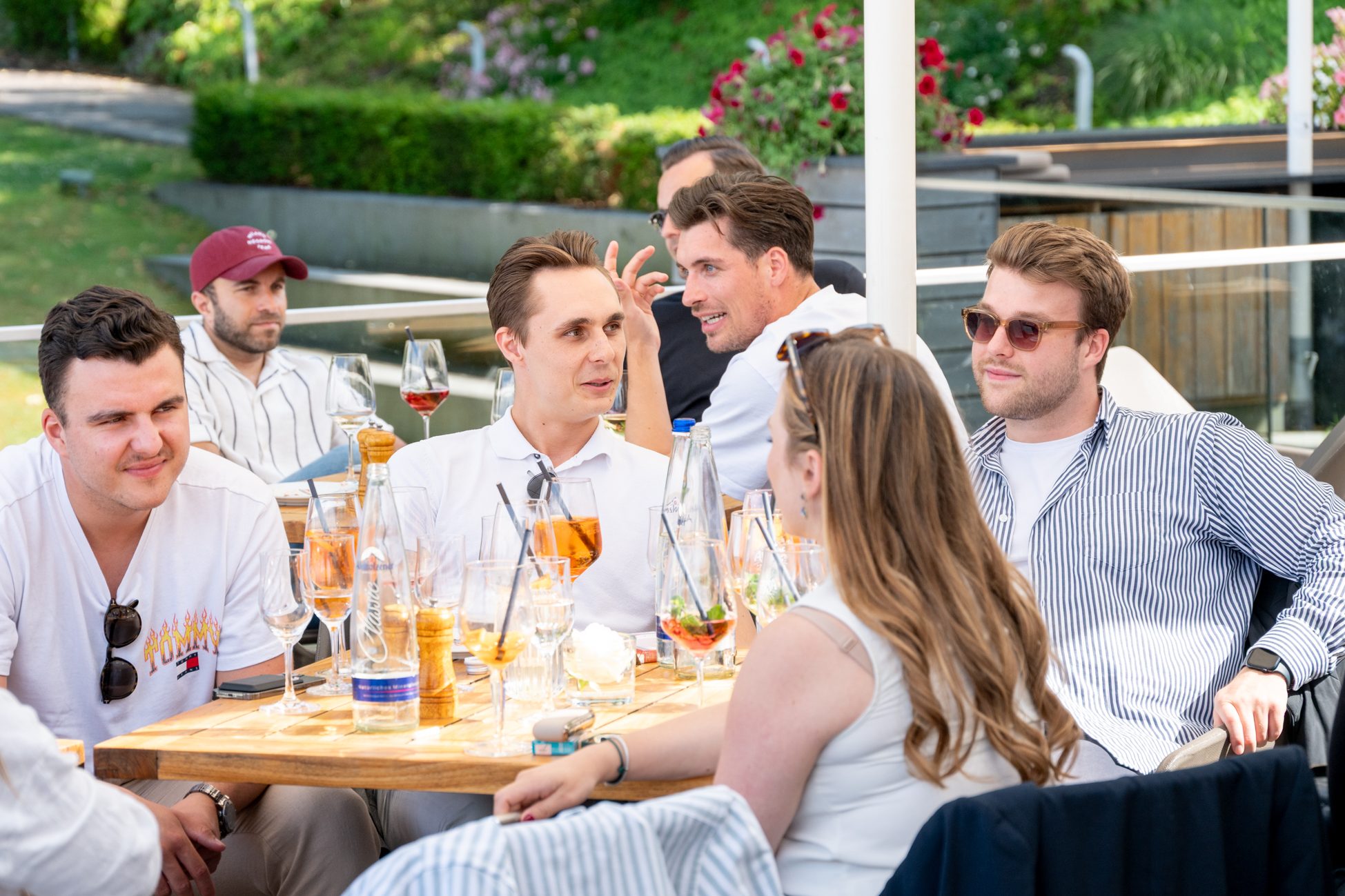 Gruppe junger Erwachsener unterhält sich bei Drinks und Sonnenschein