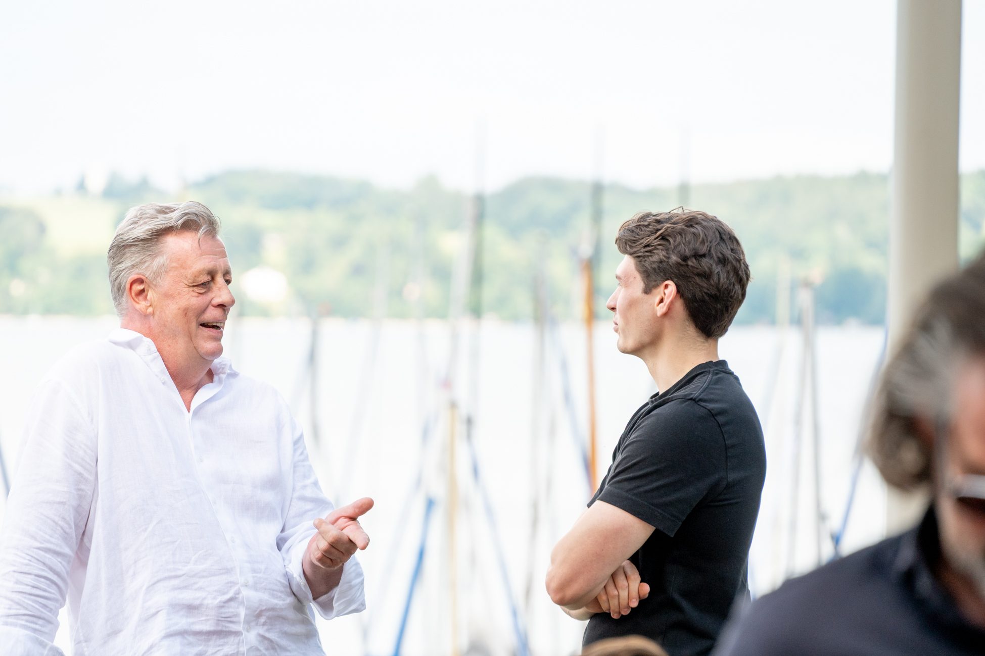 Zwei Männer im Gespräch mit Blick auf See und Segelboote