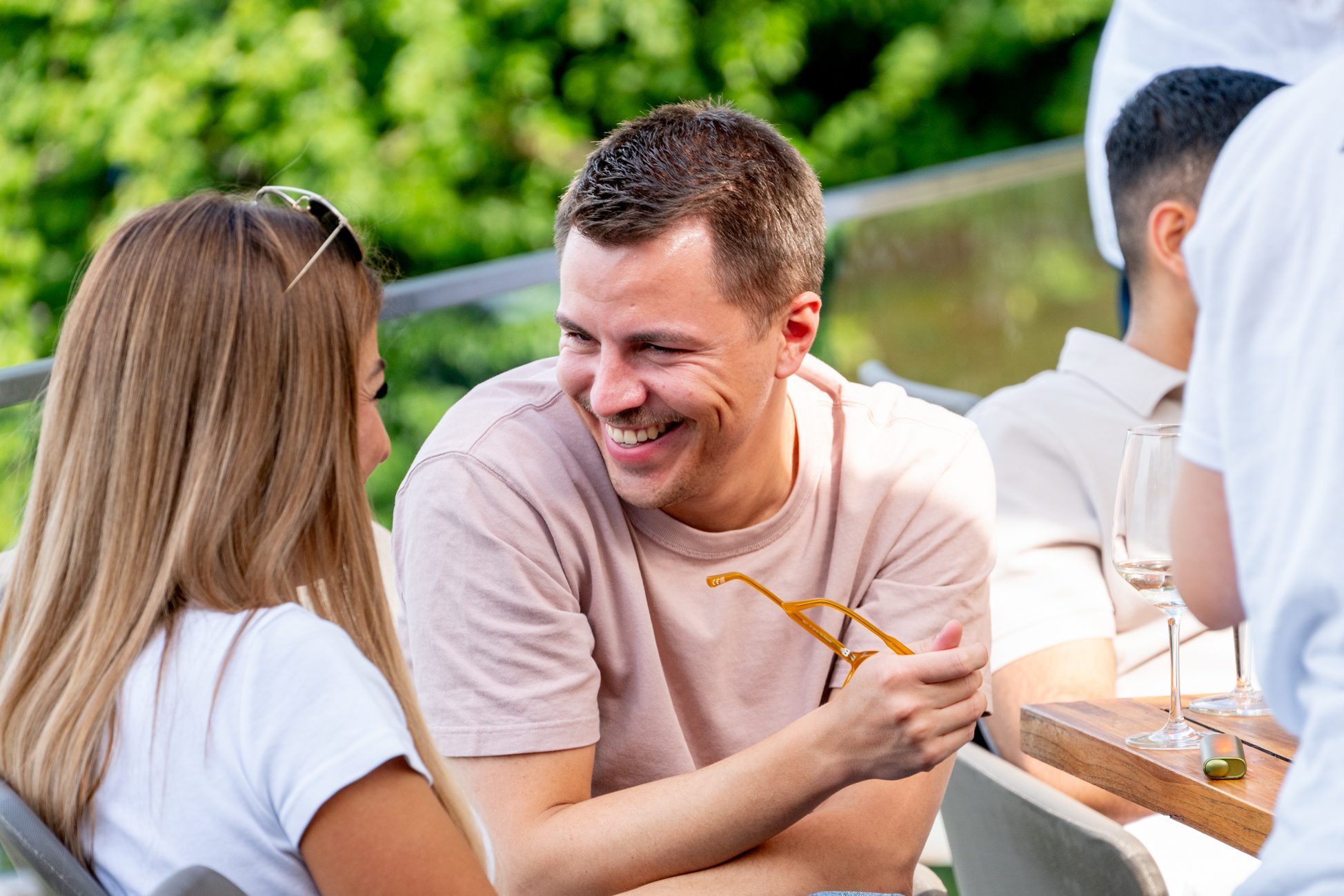 Mann und Frau im vertrauten Gespräch mit Getränken auf einer sonnigen Terrasse