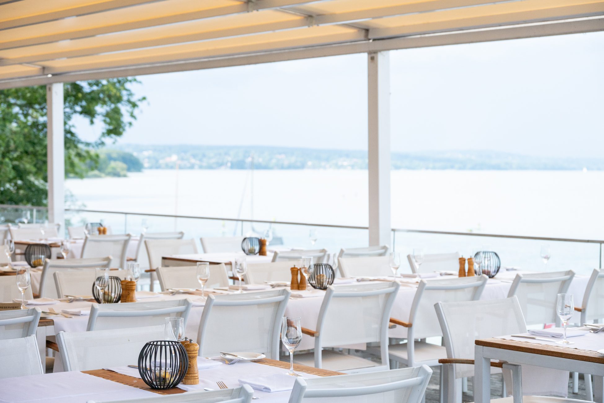 Gedeckte Tische auf einer überdachten Seeterrasse – stilvolle Eventlocation für Immobilienmakler