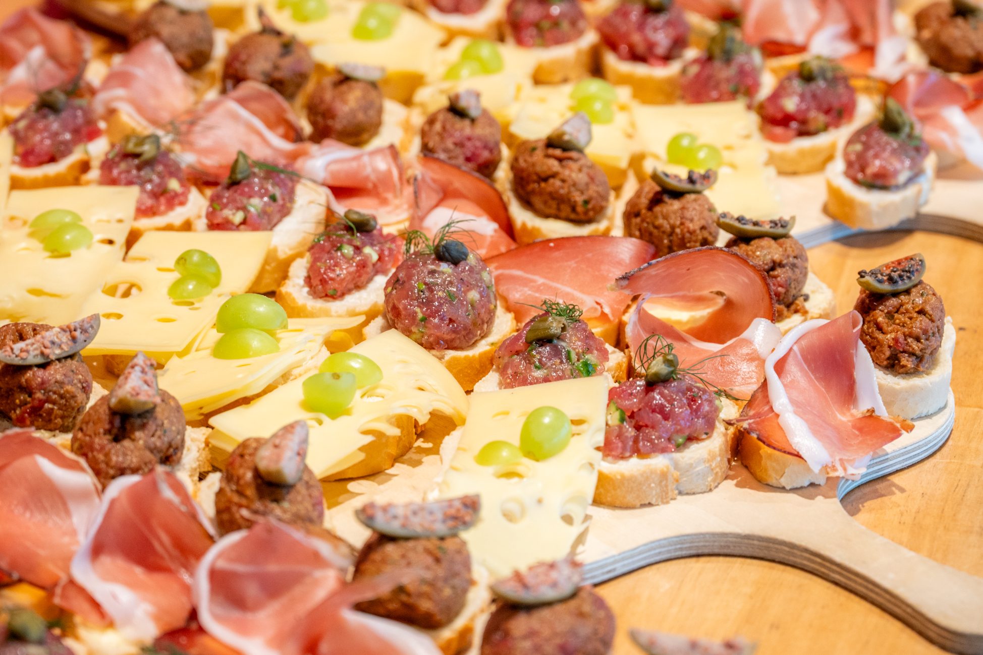 Nahaufnahme von edlen Häppchen mit Käse, Schinken und Tatar