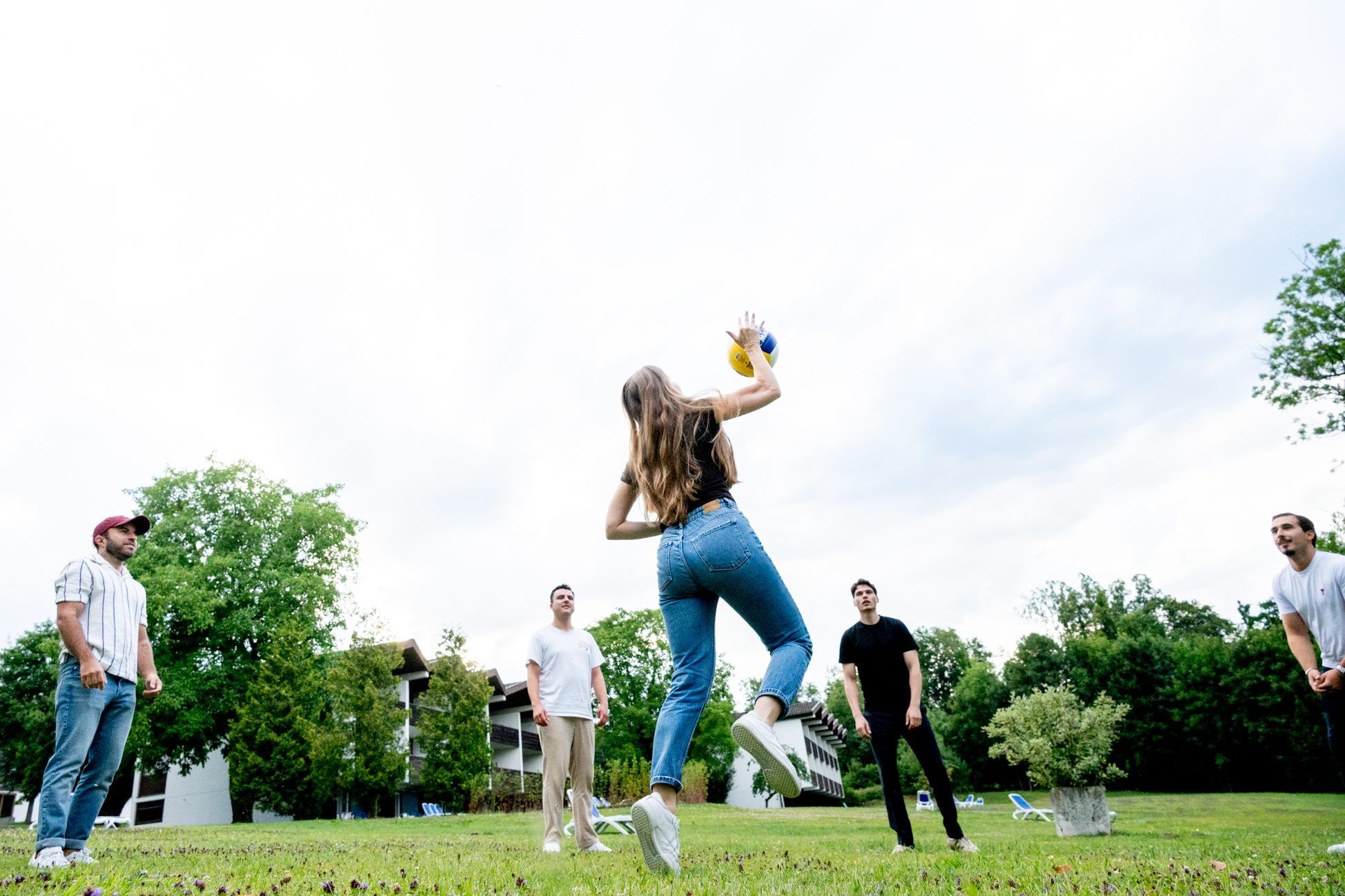 Junge Frau wirft Volleyball in der Gruppe beim Outdoor-Teamevent