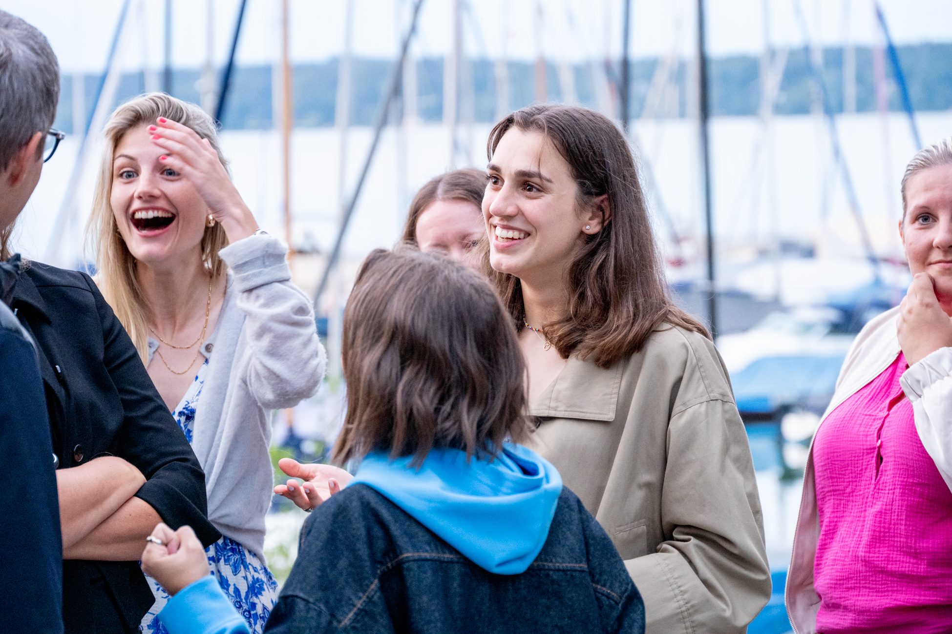 Frauen und Männer lachen gemeinsam bei abendlicher Stimmung am Steg