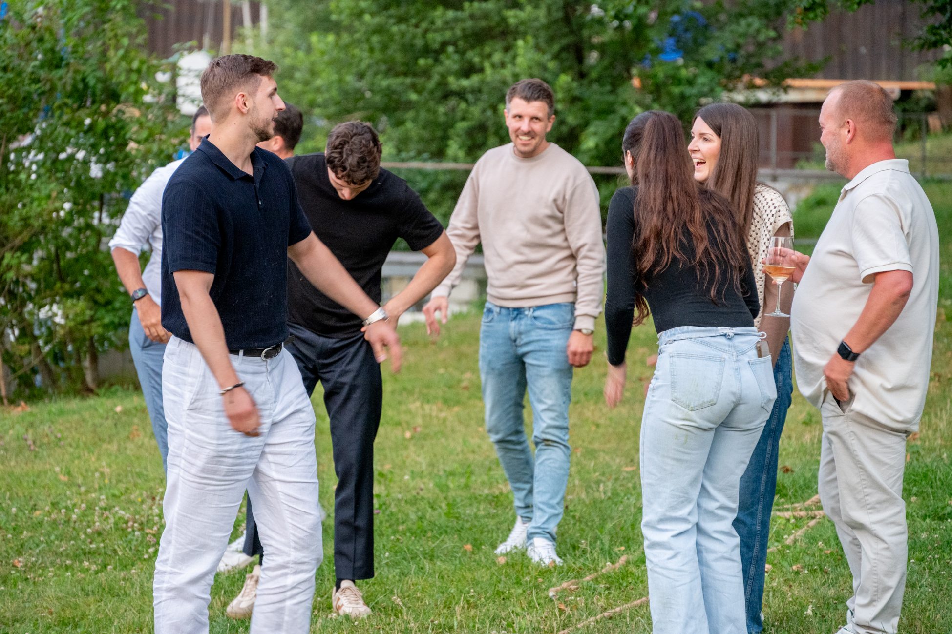 Teilnehmer des Aigner Immobilien-Sommerfests unterhalten sich entspannt nach sportlicher Aktivität auf der Wiese