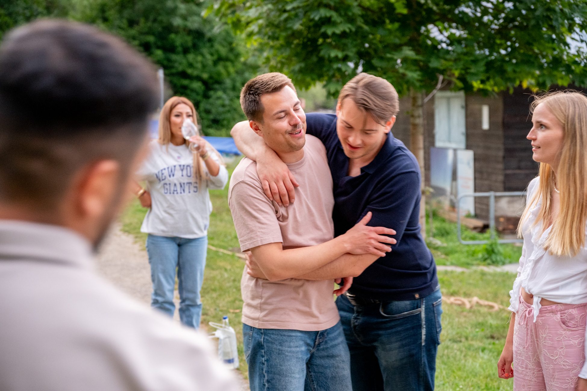 Zwei junge Männer umarmen sich lachend nach dem Eventspiel beim Aigner Immobilien-Sommerfest