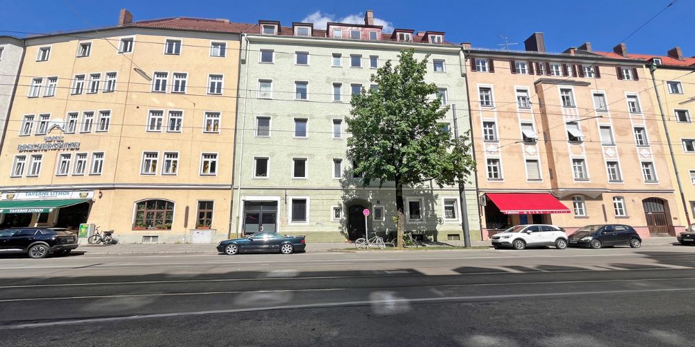 Fassadenansicht mehrerer klassischer Münchner Altbauten mit Geschäften im Erdgeschoss und Wohnraum darüber