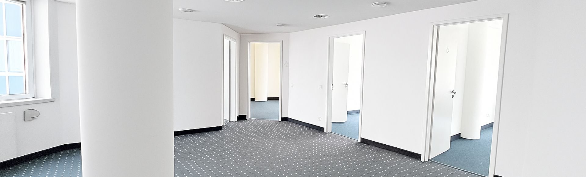 Bürofläche mit weißen Säulen und grauem Teppich