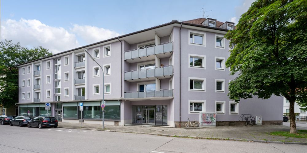 Fassade eines sanierten Mehrfamilienhauses mit Balkonen und Gewerbeeinheiten im Erdgeschoss in München