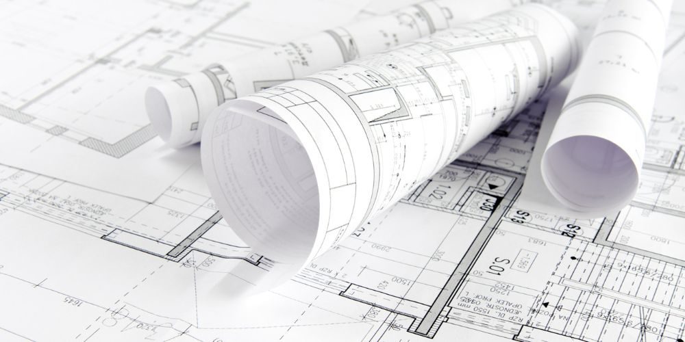 Detailreiche Architektenpläne und technische Bauzeichnungen, ausgerollt und gerollt auf einem Tisch