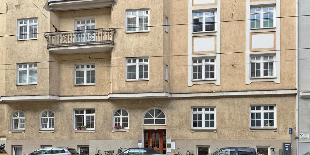 Historisches Wohn- und Geschäftshaus mit Stuckfassade, Rundbogenfenstern und Balkonen in zentraler Lage von München, ideal für Büro oder Praxis im Erdgeschoss