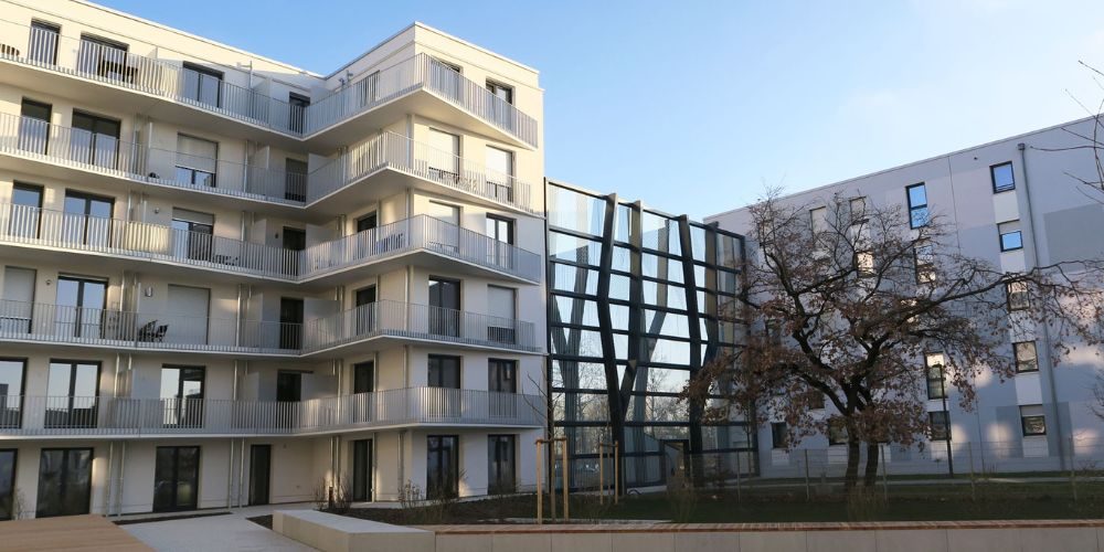 Innenhofansicht einer modernen Wohnanlage in München mit großzügigen Balkonen, Glasfassade und begrünter Außenfläche