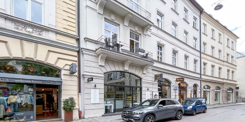 Gepflegte Altbaufassade mit vermieteten Ladenflächen in der Münchener Innenstadt, darunter Friseur, Boutique und Café