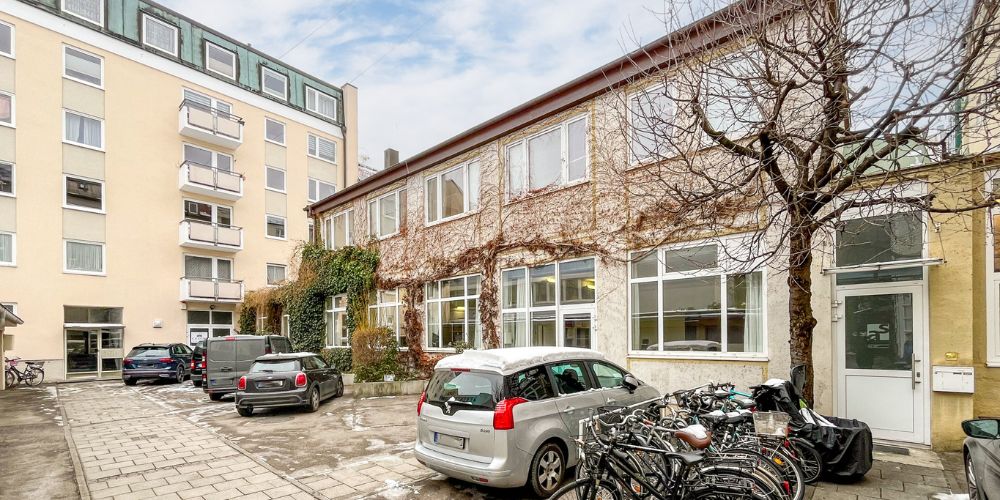 Gewerbeimmobilie mit großzügiger Fensterfront und begrünter Fassade in einem ruhigen Innenhof in München, Fahrradstellplätze und Kundenparkplätze vorhanden
