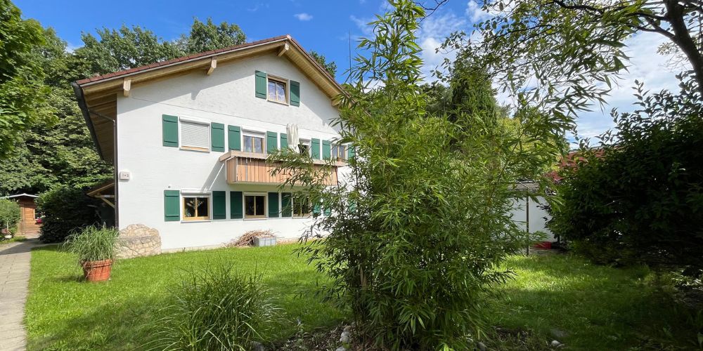 Freistehendes Mehrfamilienhaus mit grünen Fensterläden und gepflegtem Garten in ruhiger Wohnlage
