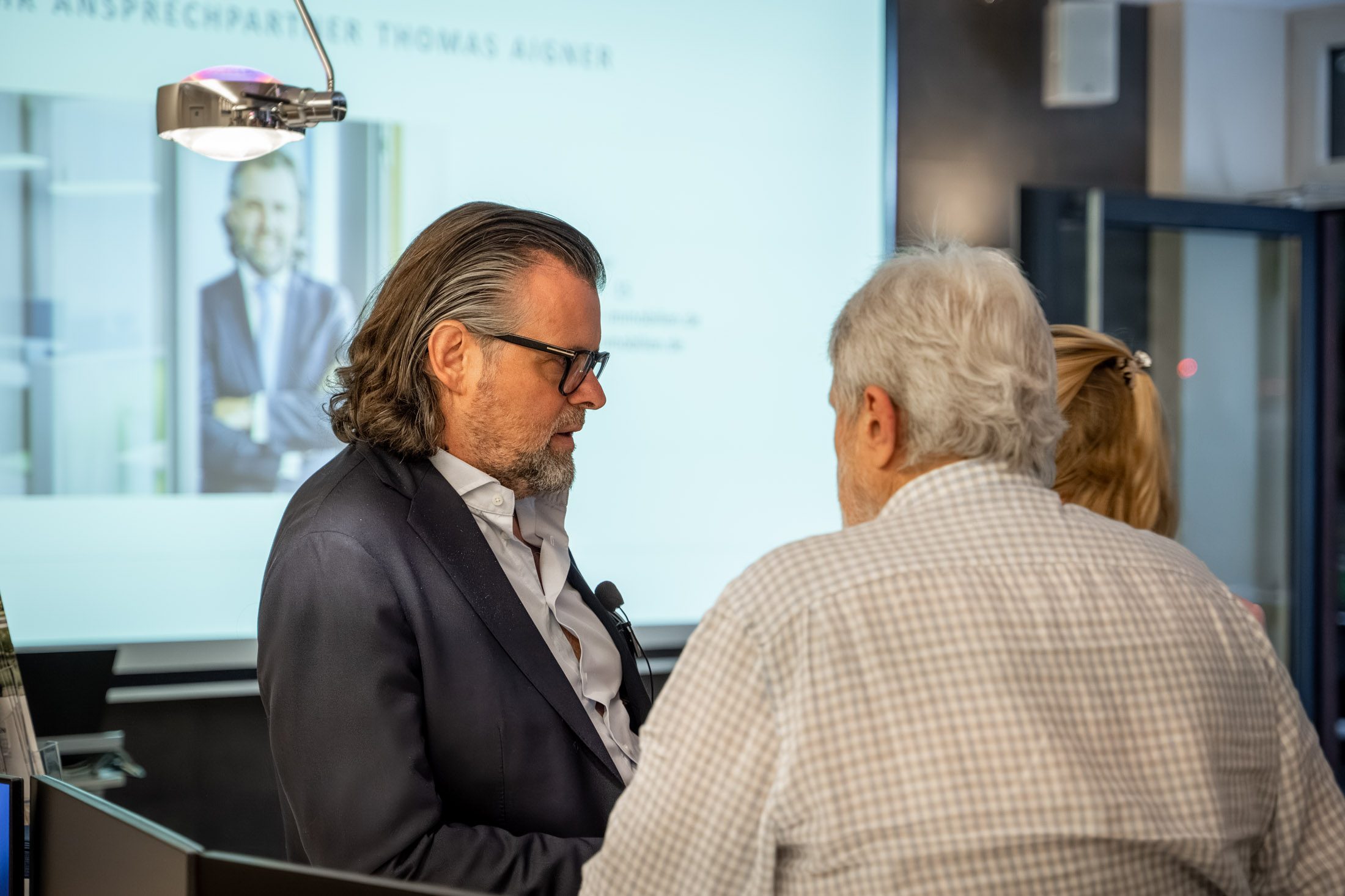 Mann im Anzug spricht mit Besucher bei Infoveranstaltung eines Immobilienmaklers